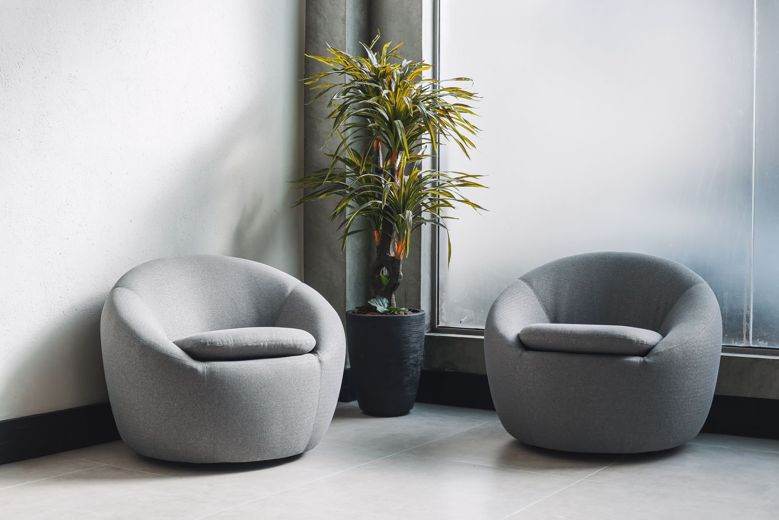 Two modern grey armchairs in a bright room